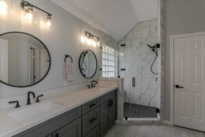 a small white bathroom with circle mirrors and marble shower